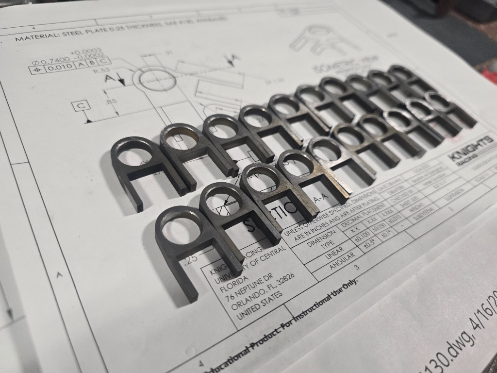 Precision laser-cut steel parts arranged on technical drawing with GD&T specifications